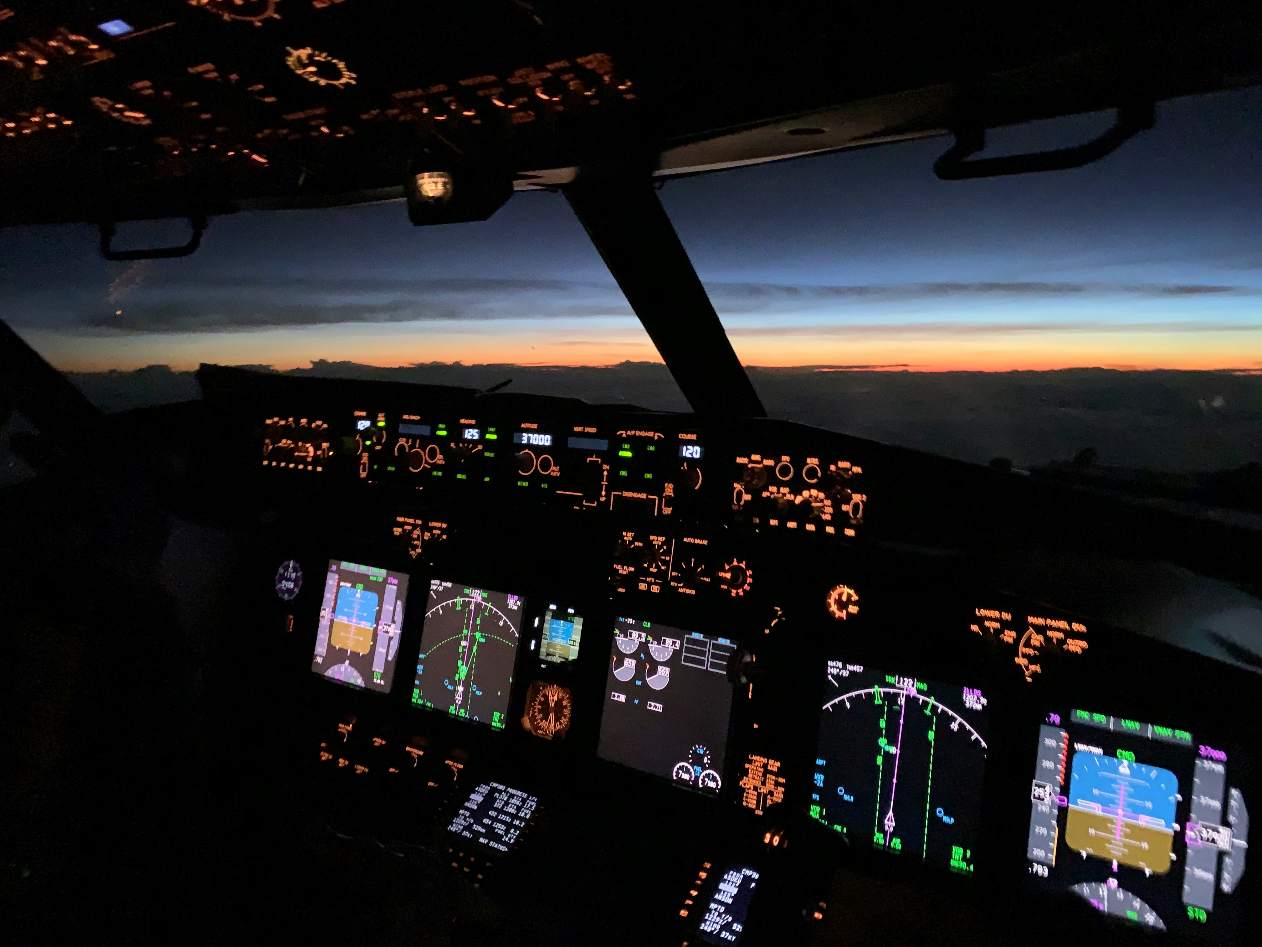 Commercial airliner cockpit at night with illuminated overhead panels